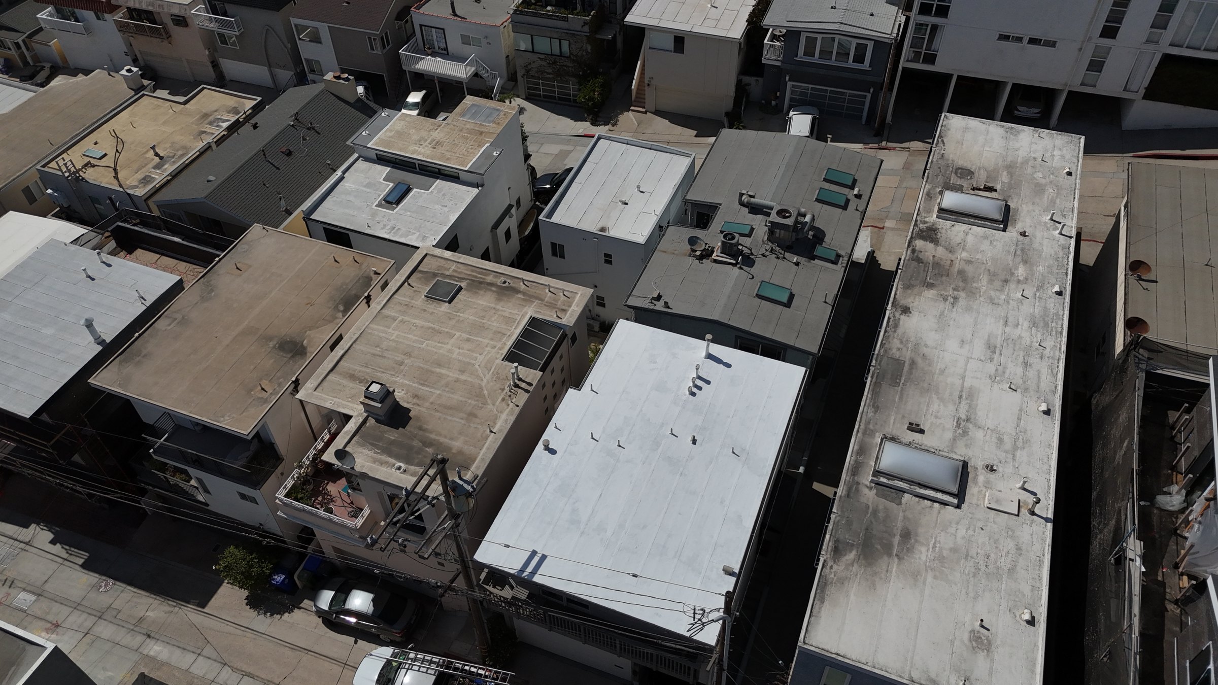 Aerial drone view of a finished white silicone roof coating on a Manhattan Beach apartment building